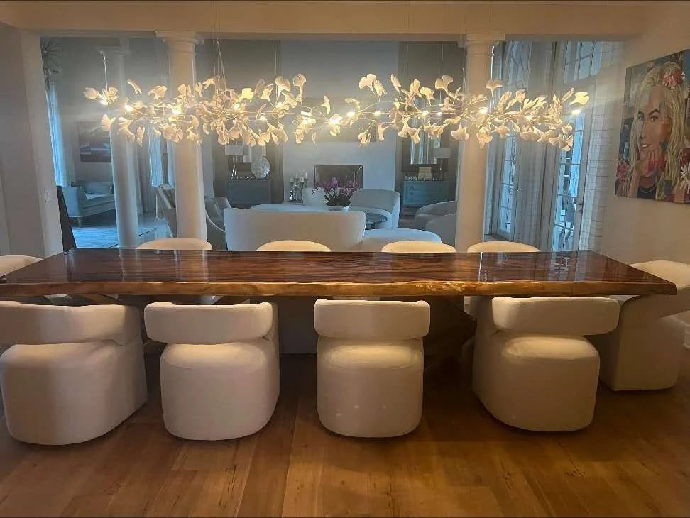 Long natural-edge wood dining table beneath a sculptural chandelier