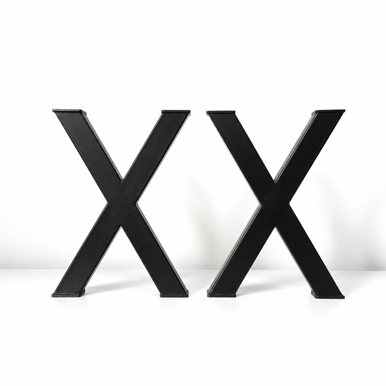 Two large black 3D letters 'X' standing side by side on a white surface against a white background.