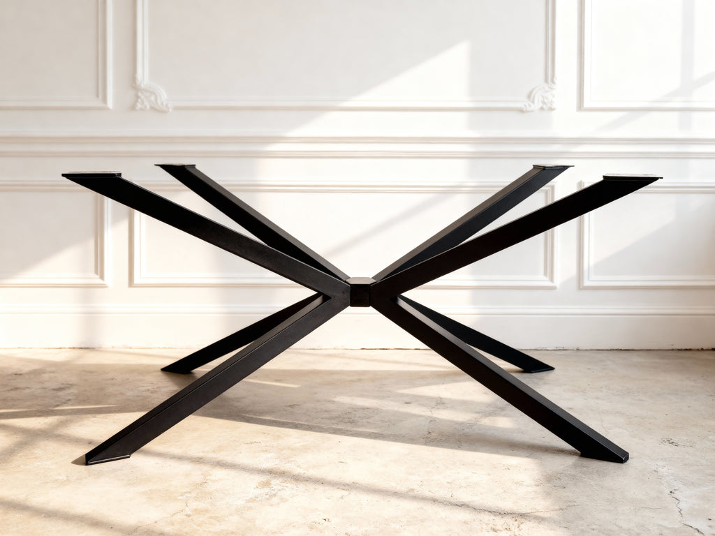 Black metal table base with X-shaped design on a light wooden floor.